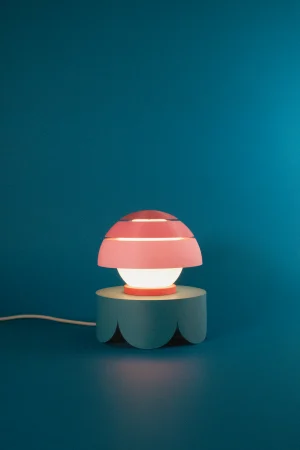Fotografía de lámpara de sobremesa Mini Four Guinda color rosa estilo diseño contemporáneo sobre fondo azul