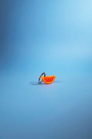 Llavero Charm gajo de naranja sobre fondo azul