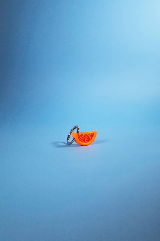 Llavero Charm gajo de naranja sobre fondo azul