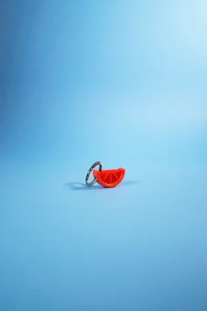 Llavero Charm gajo de pomelo sobre fondo azul