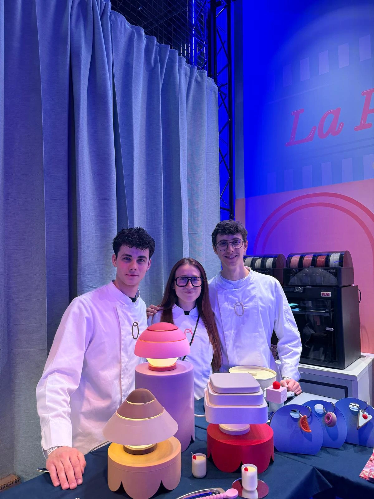 Los fundadores de PongoTodo en su stand de los La Base Awards 2026 con sus lámparas y Charms